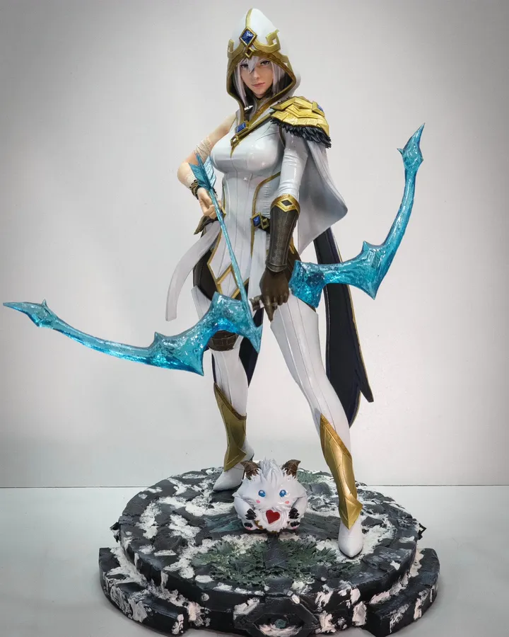 Figura pintada de una arquera de blanco y dorado con arco translúcido sobre base de piedra nevada